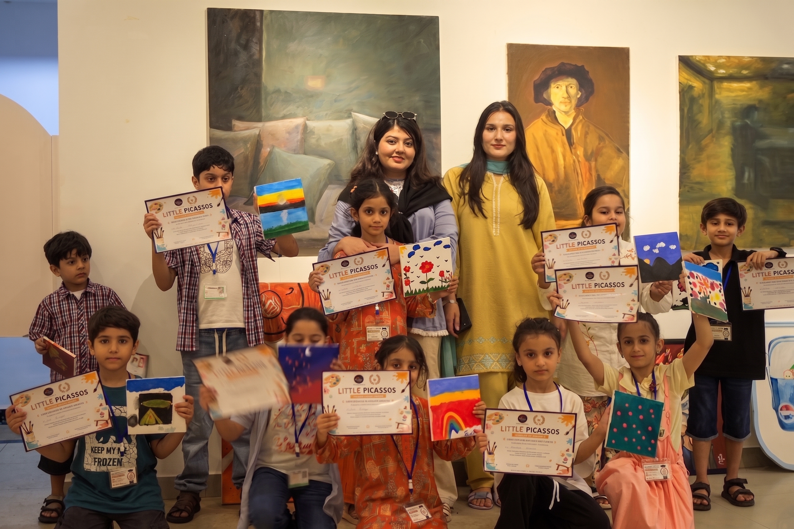 Children holding their Little Picassos art certificates and paintings